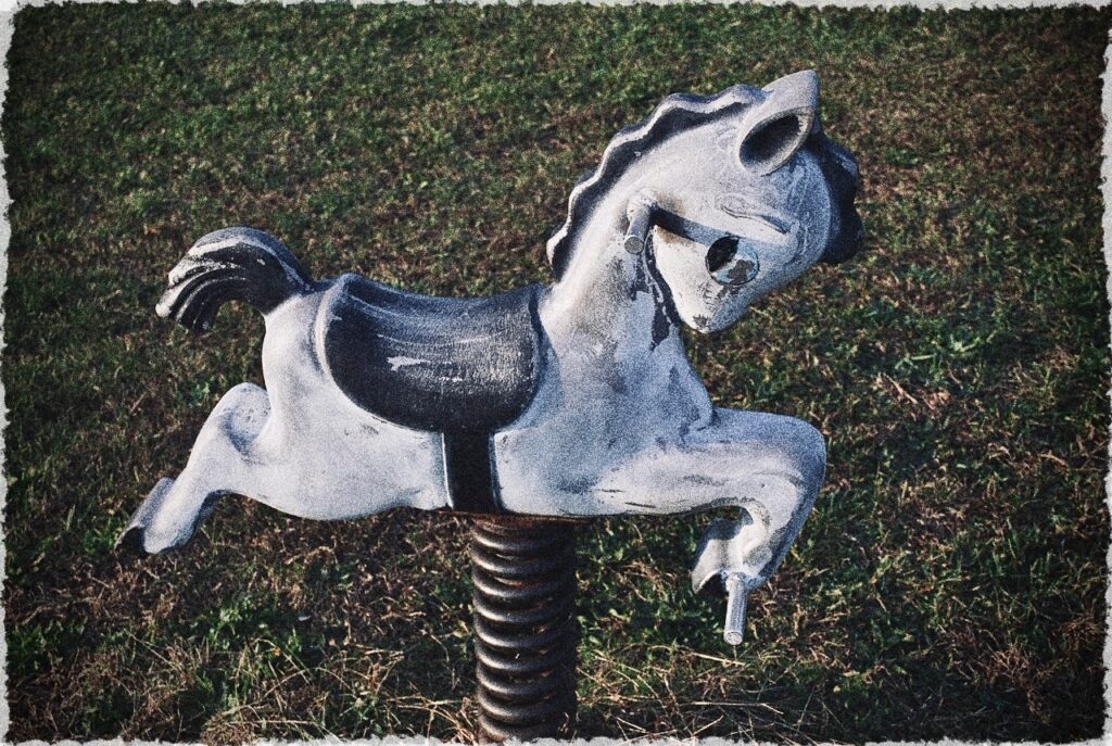 a vintage spring animal on a playground that looks like a little white horse with a saddle