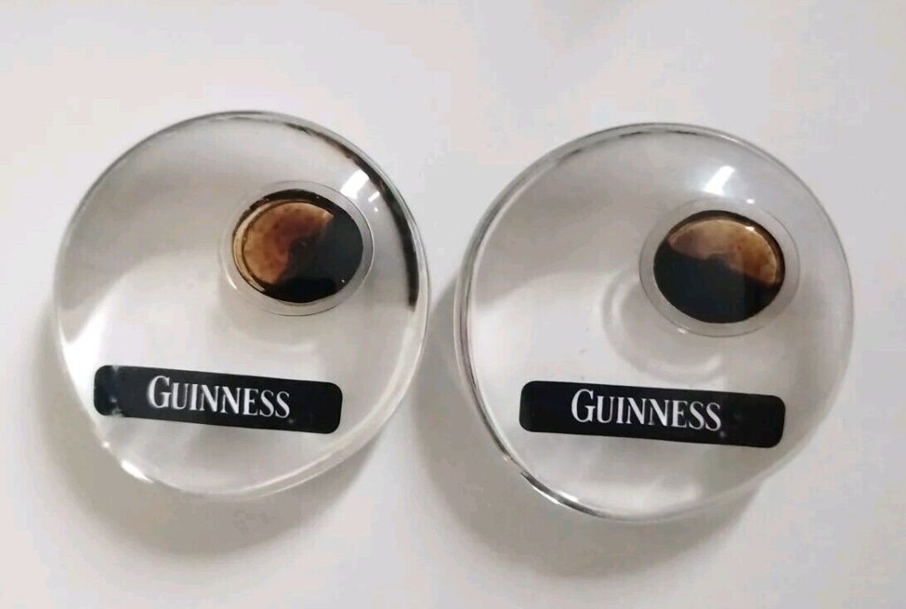 2 guinness entry token paperweights made of clear resin with a drop of guinness inside